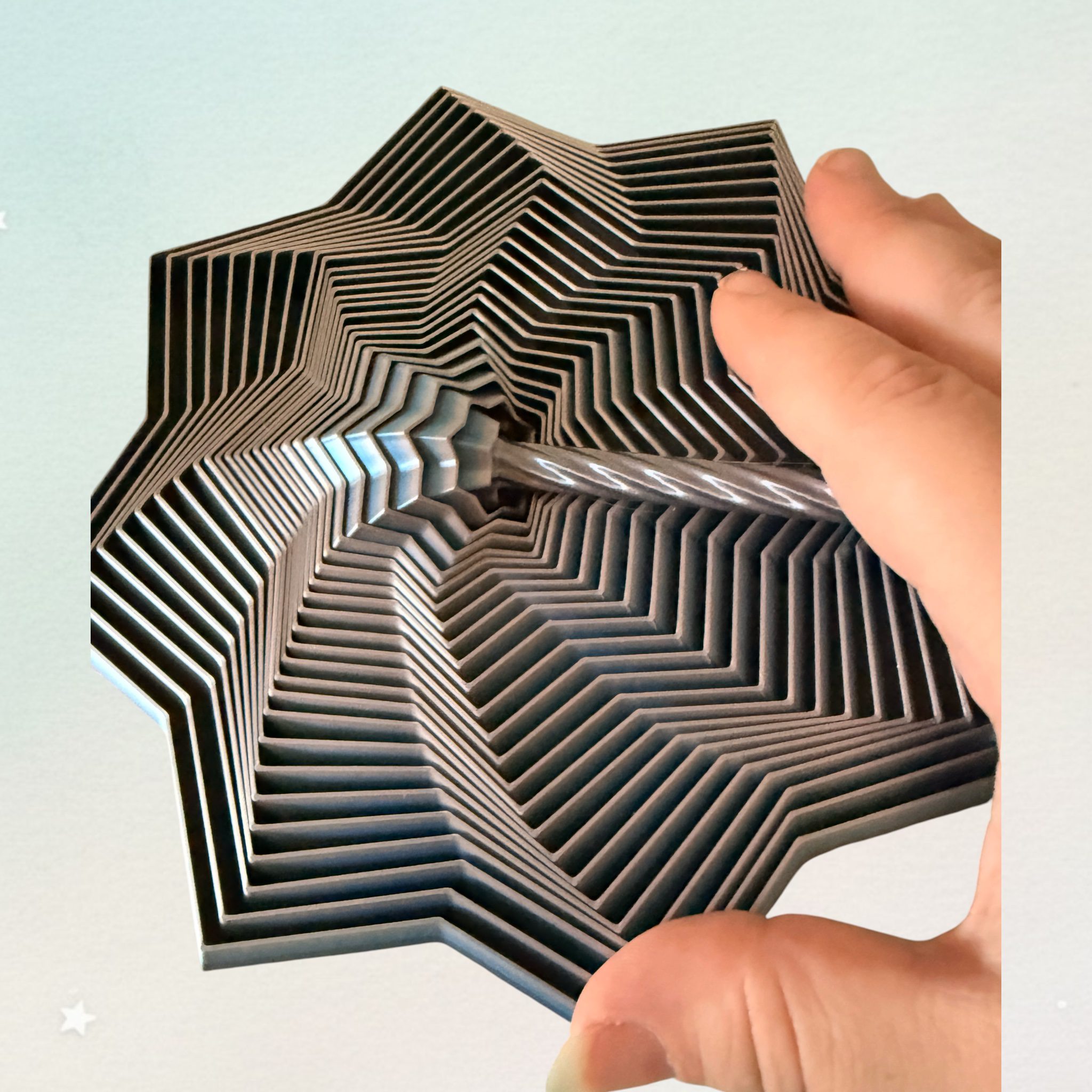 Hand hält den Spiralwirbel-Stern am Griff, Blick von oben in die Spirale